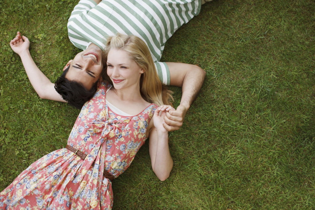 Мужчина и женщина лежат на траве и обнимаются