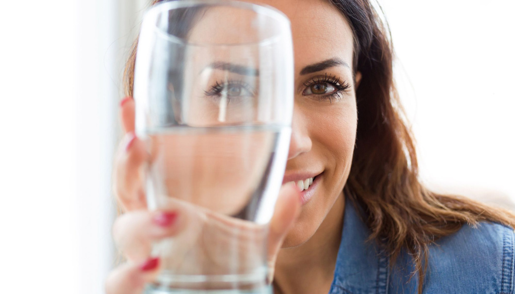 Женщина держит стакан с чистой питьевой водой